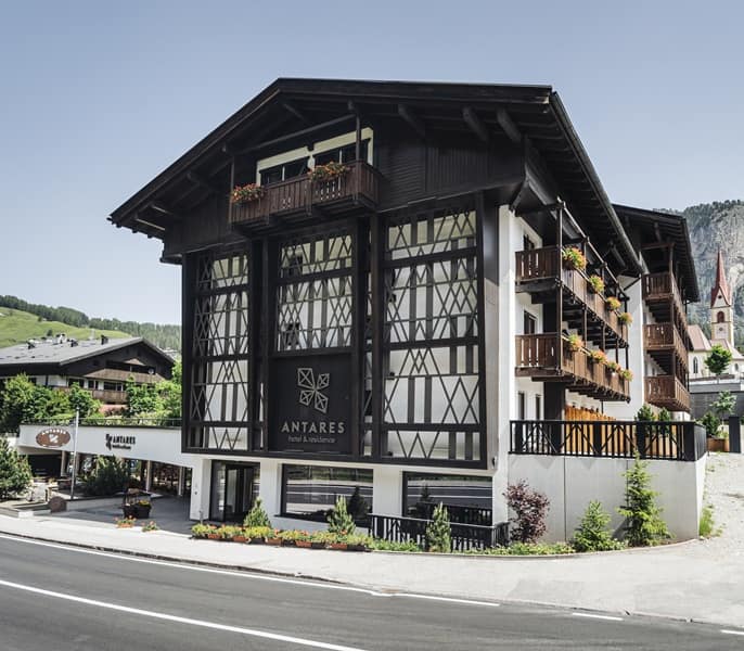 Hotel Antares: edificio montano in legno con balconi fioriti affacciato su strada