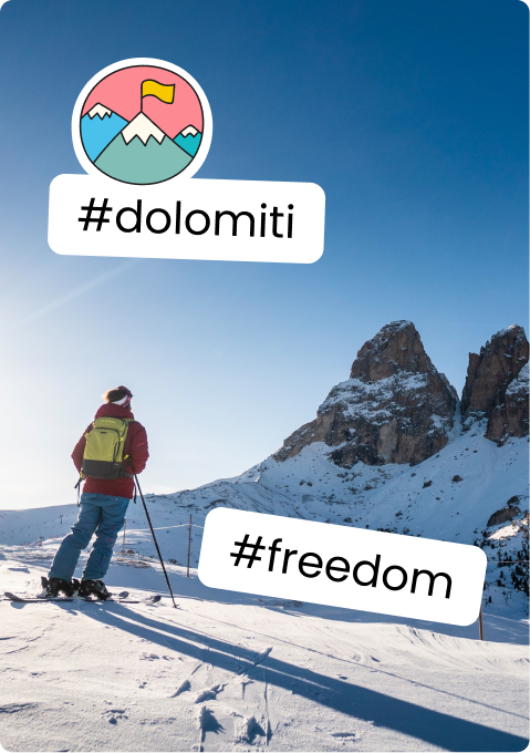 Person with backpack and poles on snowy slope facing Dolomites peaks, hashtags #dolomiti and #freedom.