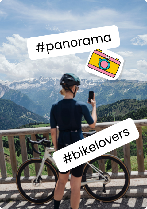 Cyclist with road bike at railing photographing snow-capped mountains; #panorama #bikelovers