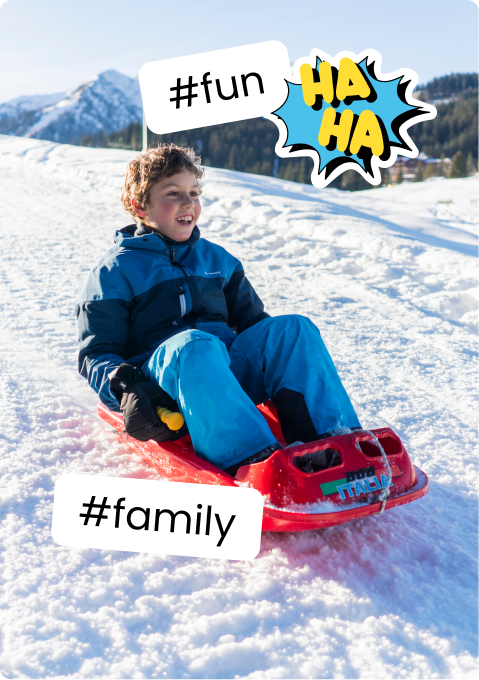 Boy sledding on red sled down snowy slope with mountains; stickers #fun #family