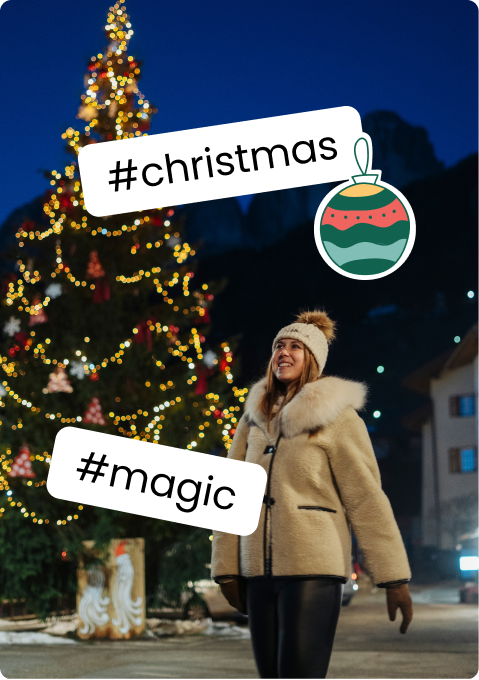 Woman in winter coat smiling beside a lit Christmas tree at night; stickers '#christmas' and '#magic'.