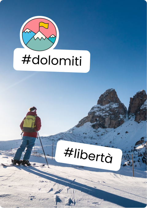 Persona con sci e zaino in piedi su pendio innevato, guarda torri rocciose; sticker #dolomiti #libertà