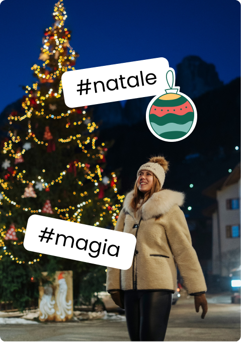Donna con cappotto peloso sorride davanti ad albero di Natale illuminato; sticker #natale e #magia
