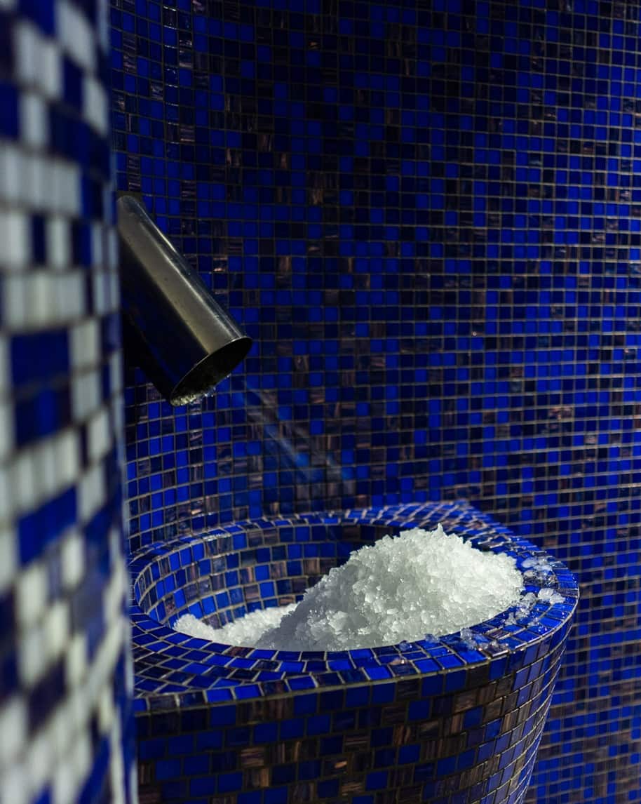 Vasca in mosaico blu con cumulo di ghiaccio tritato e bocchetta metallica sporgente