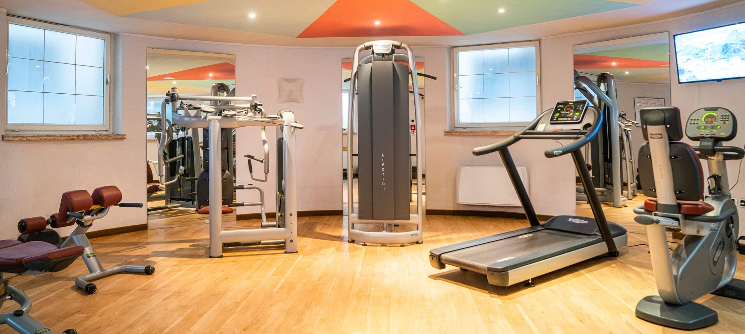 Sala fitness con tapis roulant, cyclette e macchine per la forza su pavimento in legno