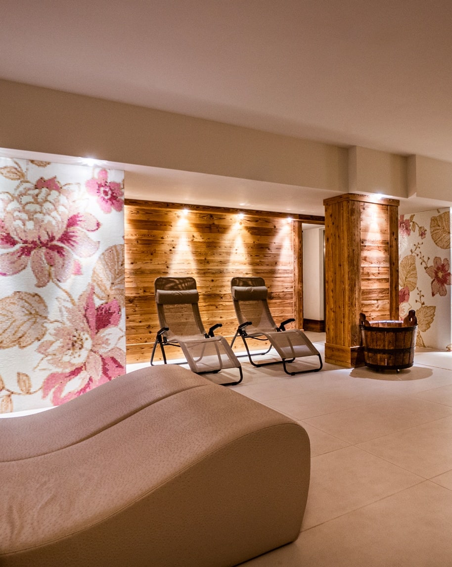 Saletta relax con due poltrone reclinabili davanti a parete in legno illuminata e chaise longue curva