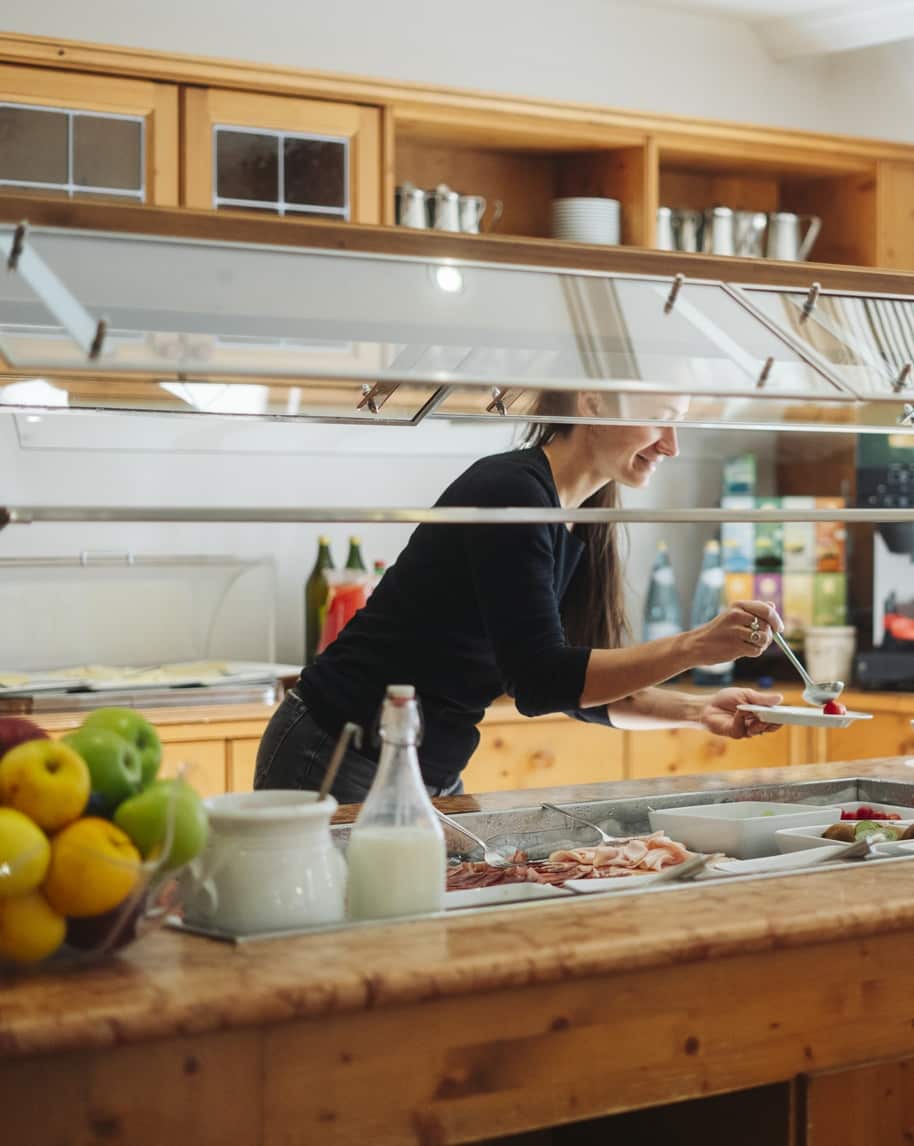 Donna che porziona cibo al bancone buffet in una sala colazione