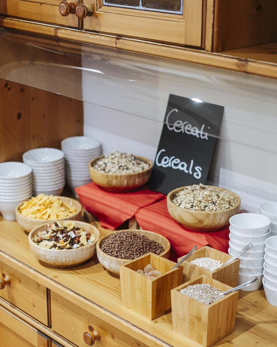 Ciotole di legno con cereali assortiti su bancone in legno, ciotole bianche impilate e lavagnetta Cereals