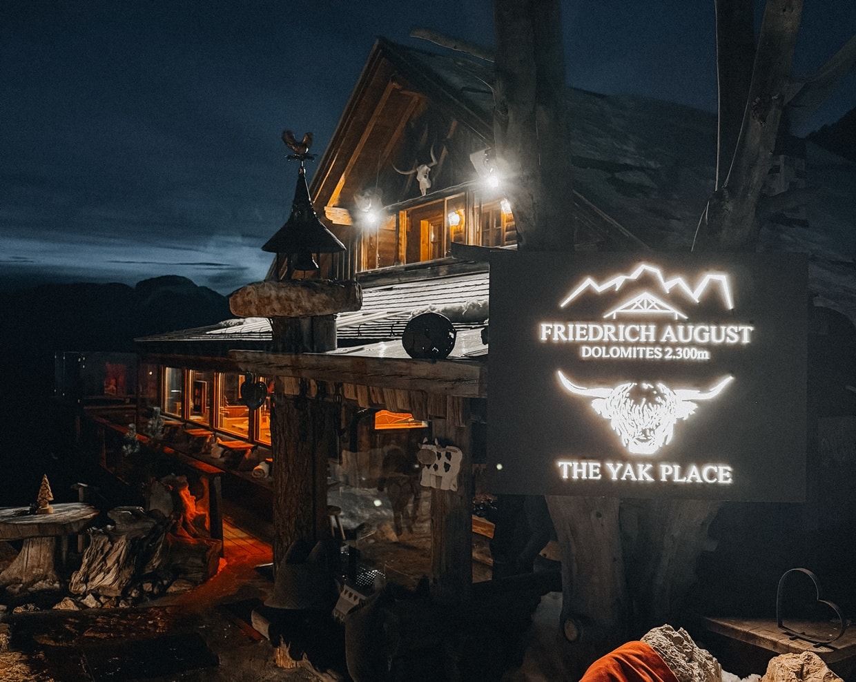 Rifugio di legno in montagna di notte con insegna illuminata FRIEDRICH AUGUST THE YAK PLACE
