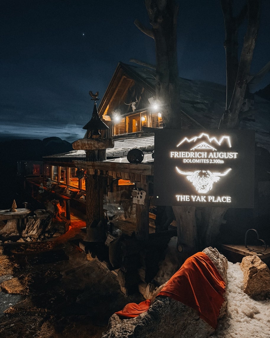 Chalet di legno Friedrich August The Yak Place illuminato di notte, coperta rossa su roccia