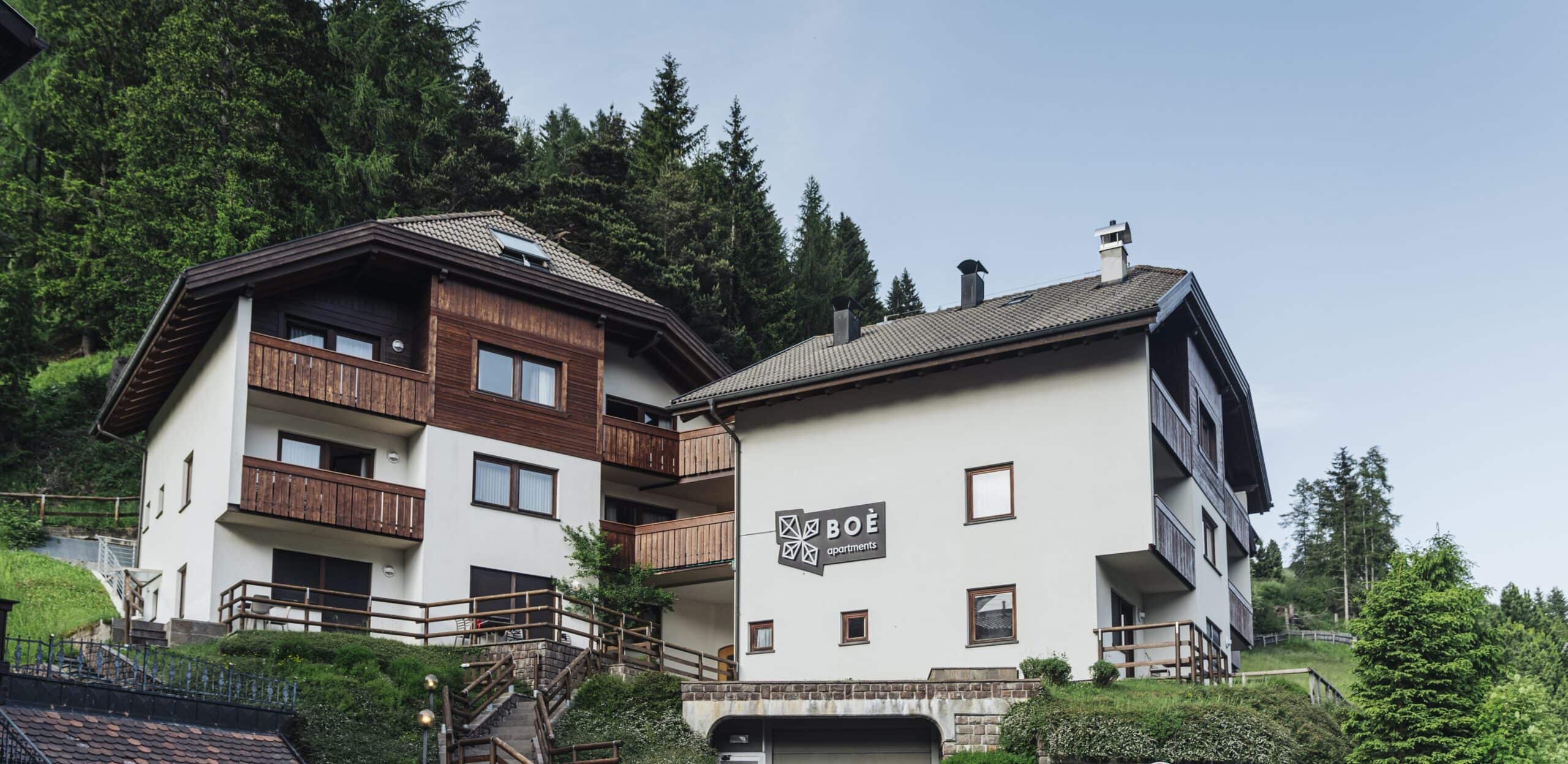 Due edifici residenziali su pendio con balconi in legno e insegna BOÈ apartments