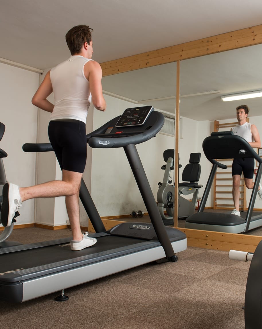 Uomo che corre su un tapis roulant in una palestra domestica, riflesso nello specchio