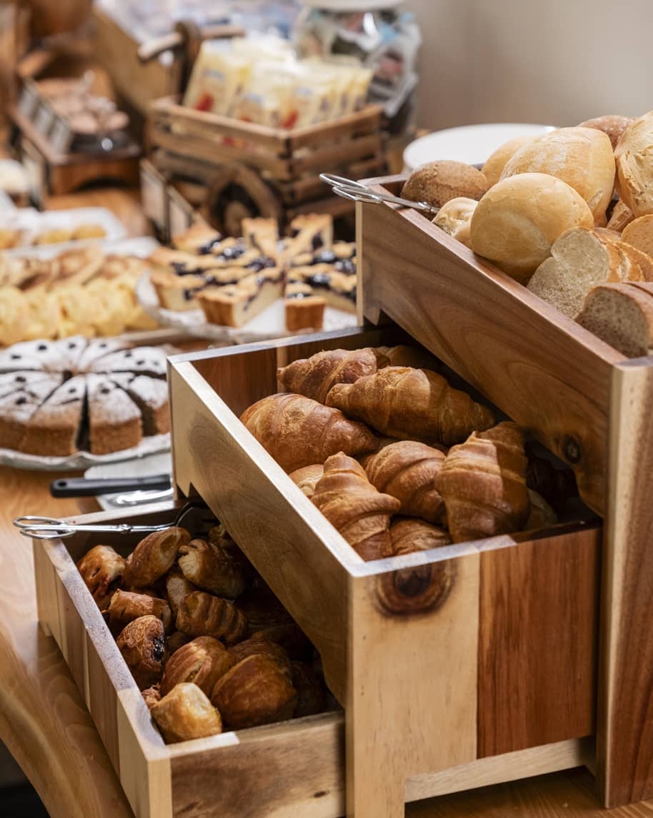 Cassetti in legno con croissant, panini e pasticcini su un tavolo da buffet