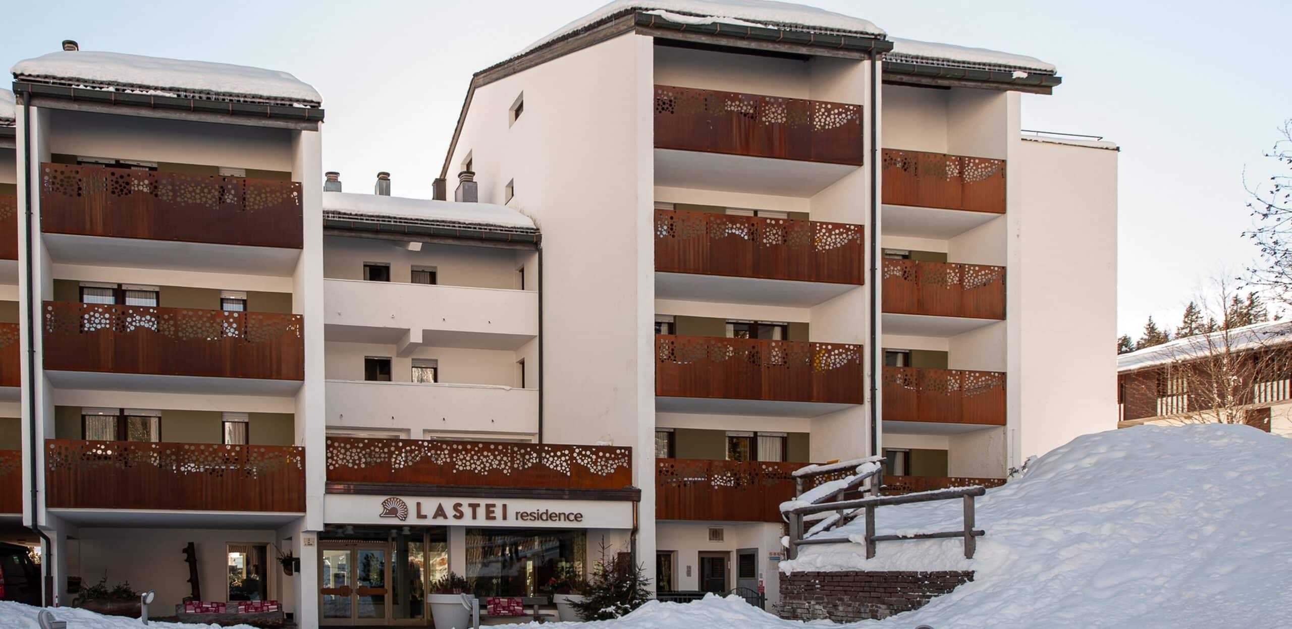 Edificio del LASTEI residence con balconi con pannelli traforati e cumuli di neve in primo piano